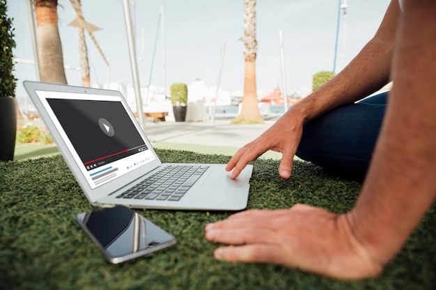 Homem do close-up ao ar livre com laptop e celular