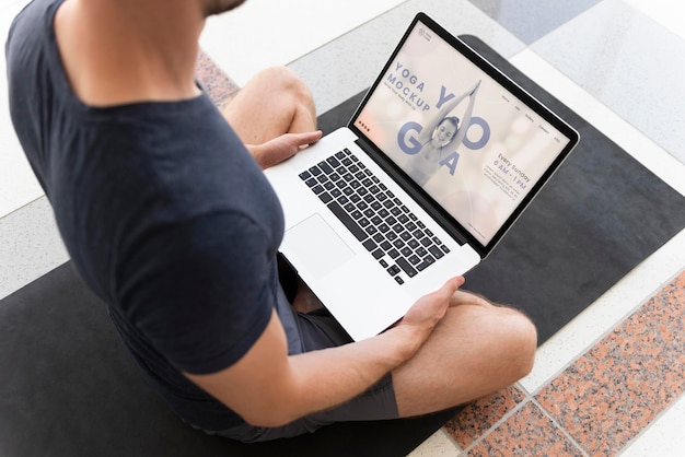 Homem fazendo ioga com design de maquete de laptop