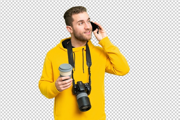 Homem fotógrafo mais jovem sobre fundo de chave de croma isolado segurando café para levar e um celular