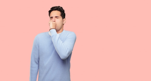 Homem jovem e bonito tosse, sofrendo uma doença de inverno, como um resfriado ou gripe