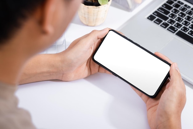 Homme à l'aide d'une maquette d'écran de smartphone au bureau blanc