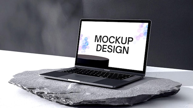 I file PSD ad alta risoluzione un portatile moderno elegante posizionato su una pietra che mostra un modello di progettazione