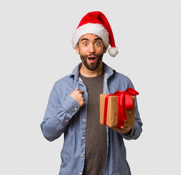 Il giovane che indossa il cappello di Babbo Natale sorpreso, si sente felice e prospera