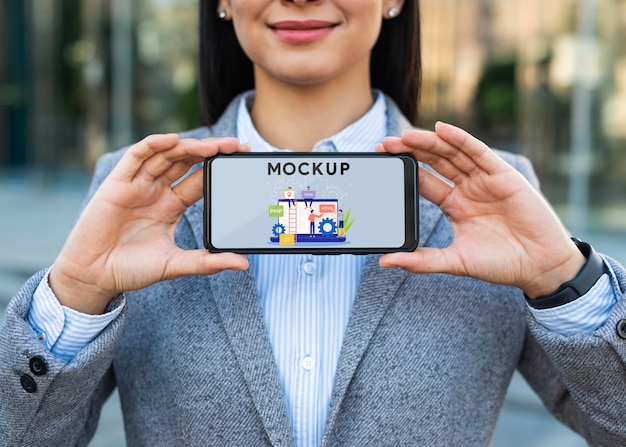 Imprenditrice all'aperto tenendo il telefono mockup