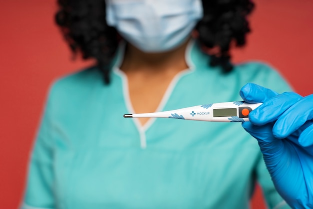 Infirmière noire avec maquette de thermomètre