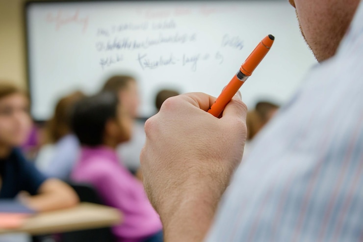 PSD insegnante con la penna in classe studenti sullo sfondo