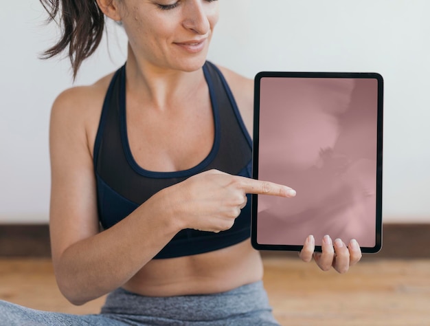 Instructor de yoga mostrando un fondo de pantalla de teléfono móvil de maqueta de tableta digital