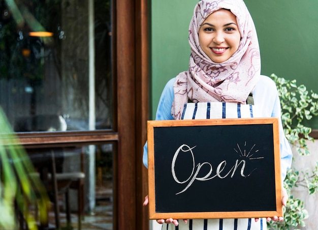 Islamische Frau, kleine Geschäftsinhaberin, die eine Tafel mit lächelndem Gesicht hält