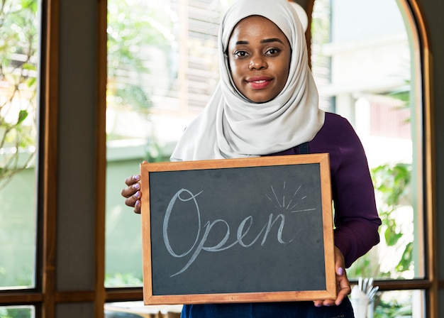 Islamischer Kleinunternehmer der Frau, der Tafel mit dem Lächeln hält