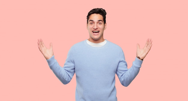 jeune bel homme avec une expression heureuse et surprise, les yeux grands ouverts et large sourire