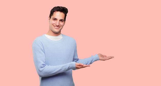 jeune bel homme souriant avec une expression satisfaite montrant un objet ou un concept avec les deux mains