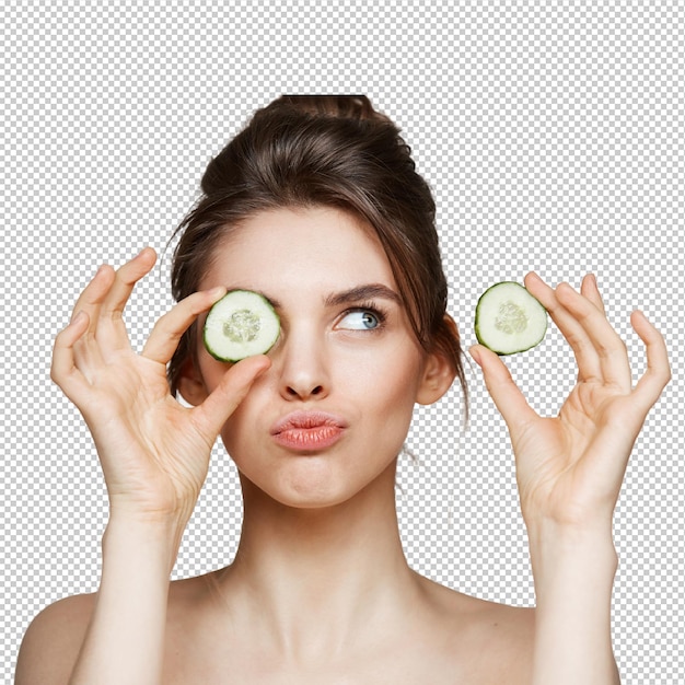 Jeune belle fille nue souriante cachant l'œil derrière une tranche de concombre sur un fond blanc concept de spa de beauté et de cosmétique