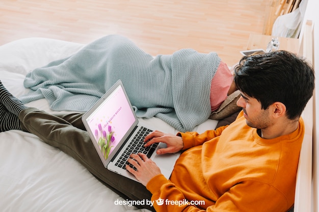 Jeune couple avec ordinateur portable au lit