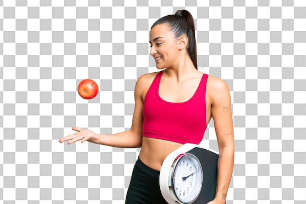 Jeune femme de beauté sur fond de clé chrome isolée avec une machine à peser et avec une pomme