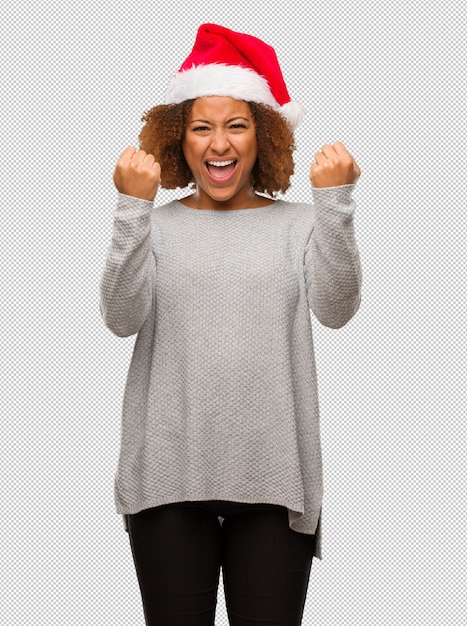 Jeune femme noire coiffée d&#39;un bonnet de Noel surprise et choquée