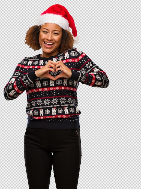 Jeune femme noire dans un pull de Noël à la mode avec impression faisant une forme de coeur avec les mains