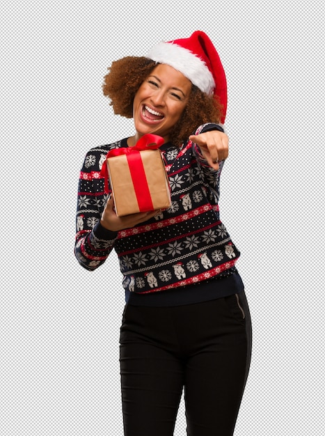 Jeune femme noire tenant un cadeau joyeux et souriant au jour de Noël