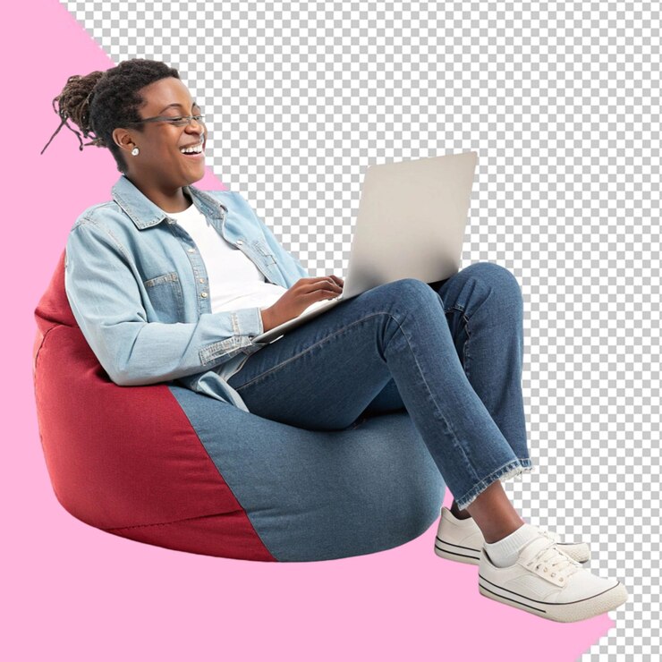 Une jeune femme travaille sur un ordinateur portable et est assise dans une chaise paresseuse.
