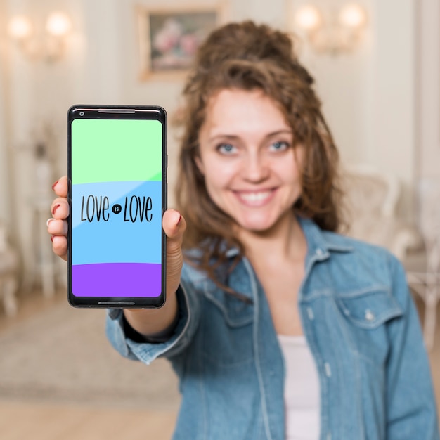 Jeune fille souriante présentant la maquette d&#39;un smartphone