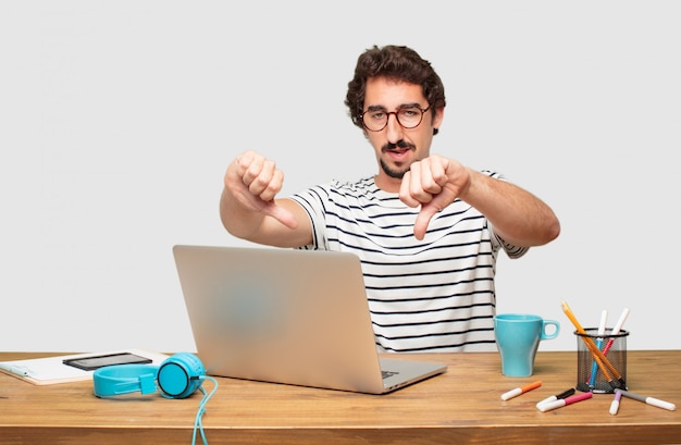 PSD jeune graphiste barbu avec un ordinateur portable avec une expression dissidente, sérieuse et sévère