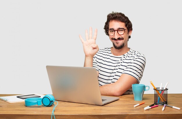 PSD jeune graphiste barbu avec un ordinateur portable souriant et l'air satisfait et heureux