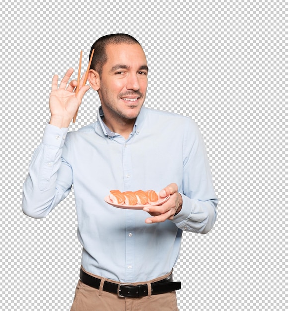 Jeune homme à l'aide de baguettes pour manger des sushis