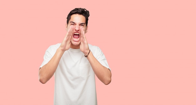 jeune homme beau criant fort comme un fou, appelant avec la main avec une expression en colère