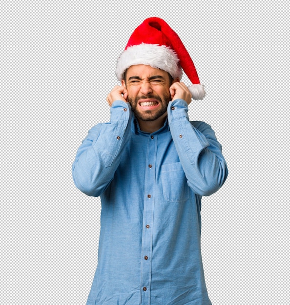 Jeune homme portant bonnet de Noel couvrant les oreilles avec les mains