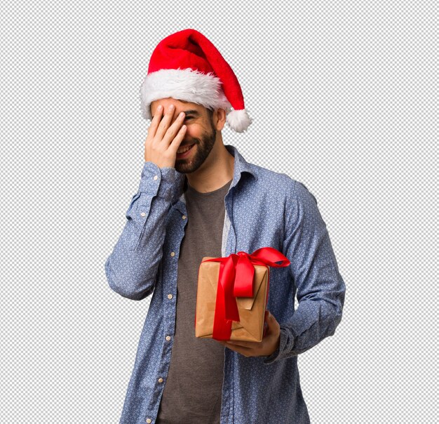 PSD jeune homme portant le bonnet de noel embarrassé et riant en même temps