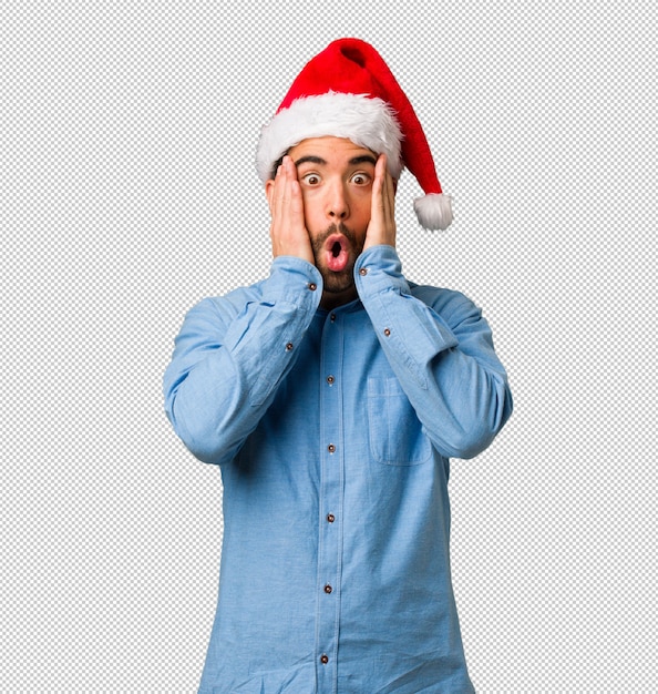 Jeune homme portant le bonnet de Noel surpris et choqué