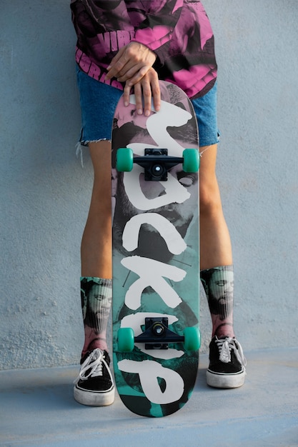 Jeune personne avec des vêtements frais tenant un skateboard à l'extérieur