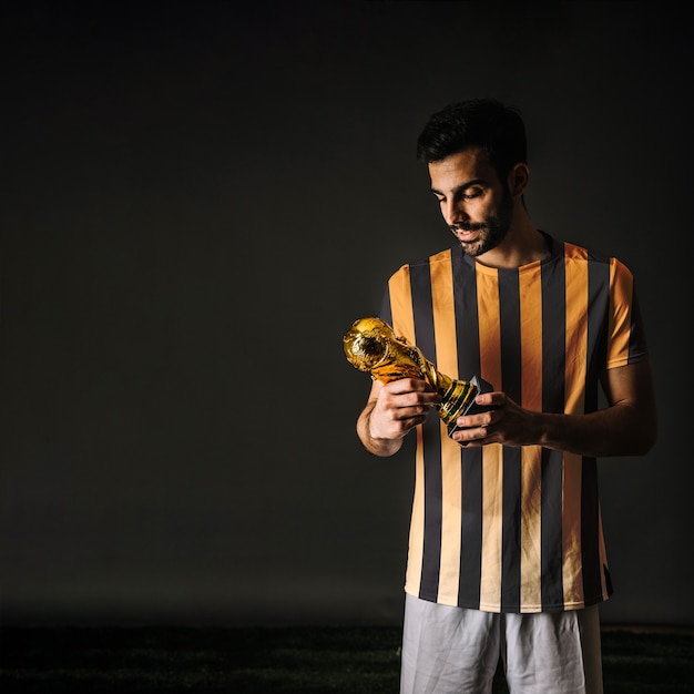 Jogador de futebol, olhando troféu