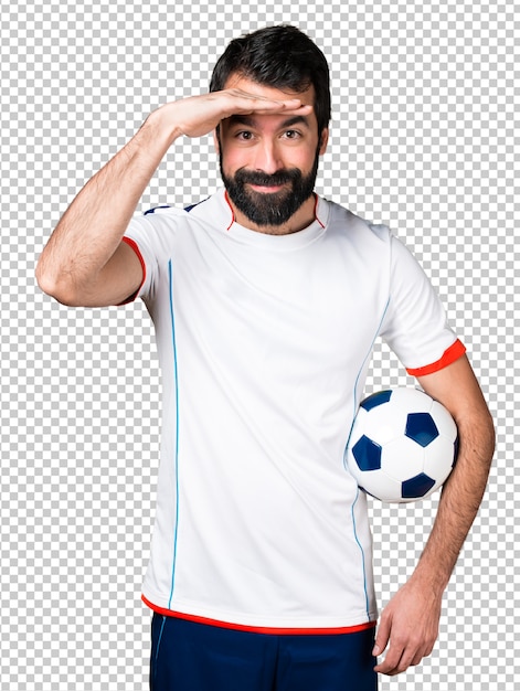 Jogador de futebol, segurando uma bola de futebol, mostrando algo