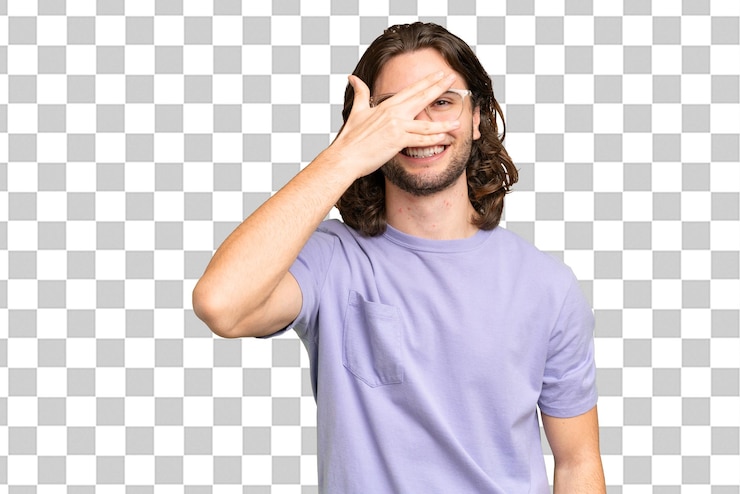 PSD jovem bonito sobre fundo isolado, cobrindo os olhos pelas mãos e sorrindo