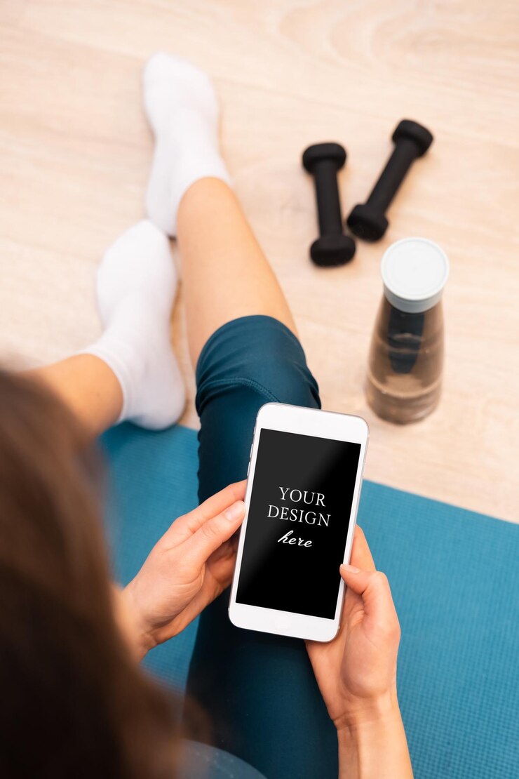 Jovem descansando após treino sentado no chão e segurando a tela em branco do smartphone com área para design ou texto
