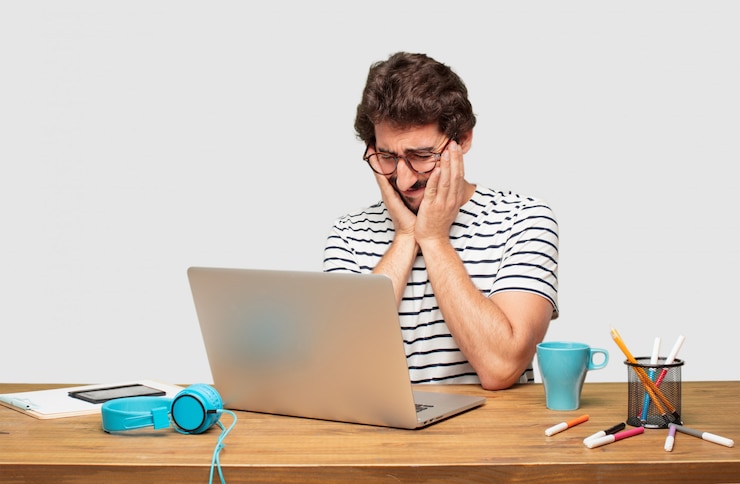 PSD jovem designer gráfico barbudo com um laptop com um olhar triste de decepção e derrota