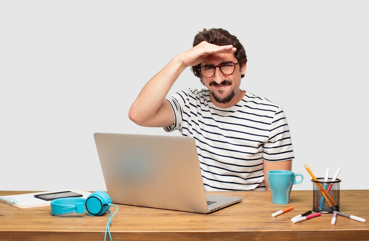 PSD jovem designer gráfico barbudo com um laptop olhando longe na distância