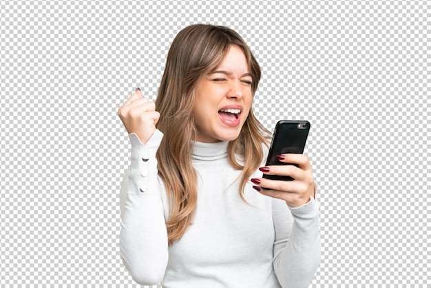 Jovem garota sobre fundo de chave de croma isolado usando telefone móvel e fazendo gesto de vitória