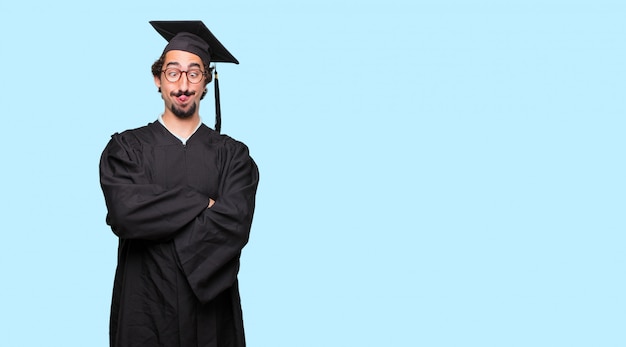jovem graduado brincando, furando a língua com uma expressão engraçada, boba e brincalhão