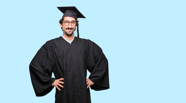 jovem graduado com um olhar orgulhoso, satisfeito e feliz, com as duas mãos nos quadris