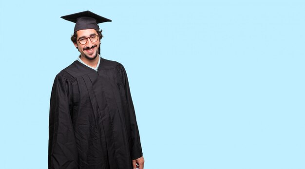 jovem graduado com um olhar orgulhoso, satisfeito e feliz, com as duas mãos nos quadris