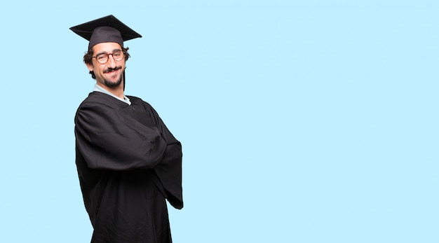 jovem graduado com um olhar orgulhoso, satisfeito e feliz no rosto, sorrindo com os braços cruzados