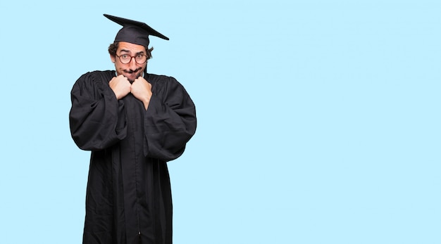 Jovem graduado gritando, parecendo surpreso, estressado e aterrorizado, com um gesto de asfixia