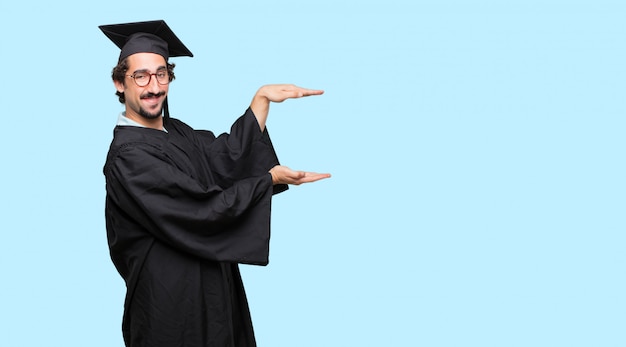 Jovem graduado sorrindo com uma expressão satisfeita mostrando um objeto ou conceito