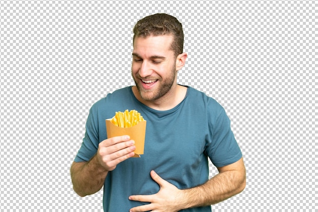 Jovem homem loiro bonito segurando batatas fritas sobre fundo de chave de croma isolado sorrindo muito