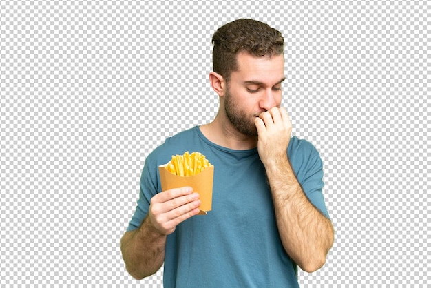Jovem homem loiro bonito segurando batatas fritas sobre fundo de chave de croma isolado tendo dúvidas