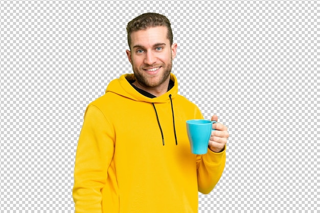 Jovem homem loiro bonito segurando uma xícara de café sobre um fundo isolado sorrindo muito