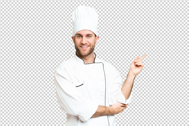 Jovem homem loiro Chef sobre isolado chroma chave fundo apontando o dedo para o lado