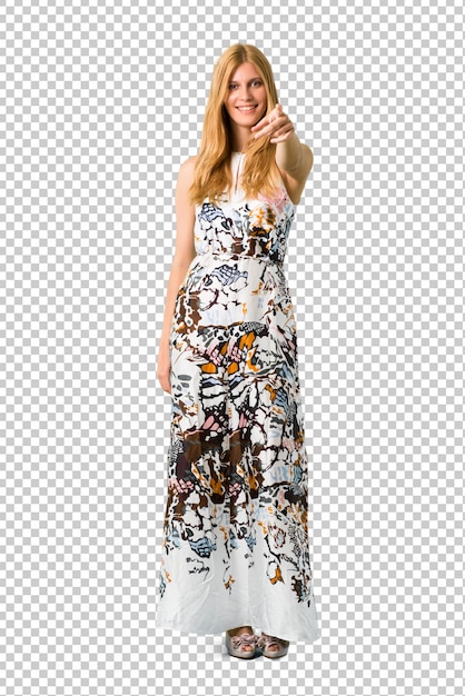 Jovem loira em um vestido de verão aponta o dedo para você com uma expressão confiante