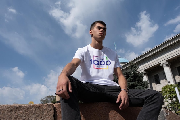 Joven con camiseta blanca y vaqueros frente al edificio